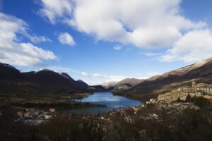 Lago di Tenno con acque turchesi e il borgo medievale sullo sfondo.