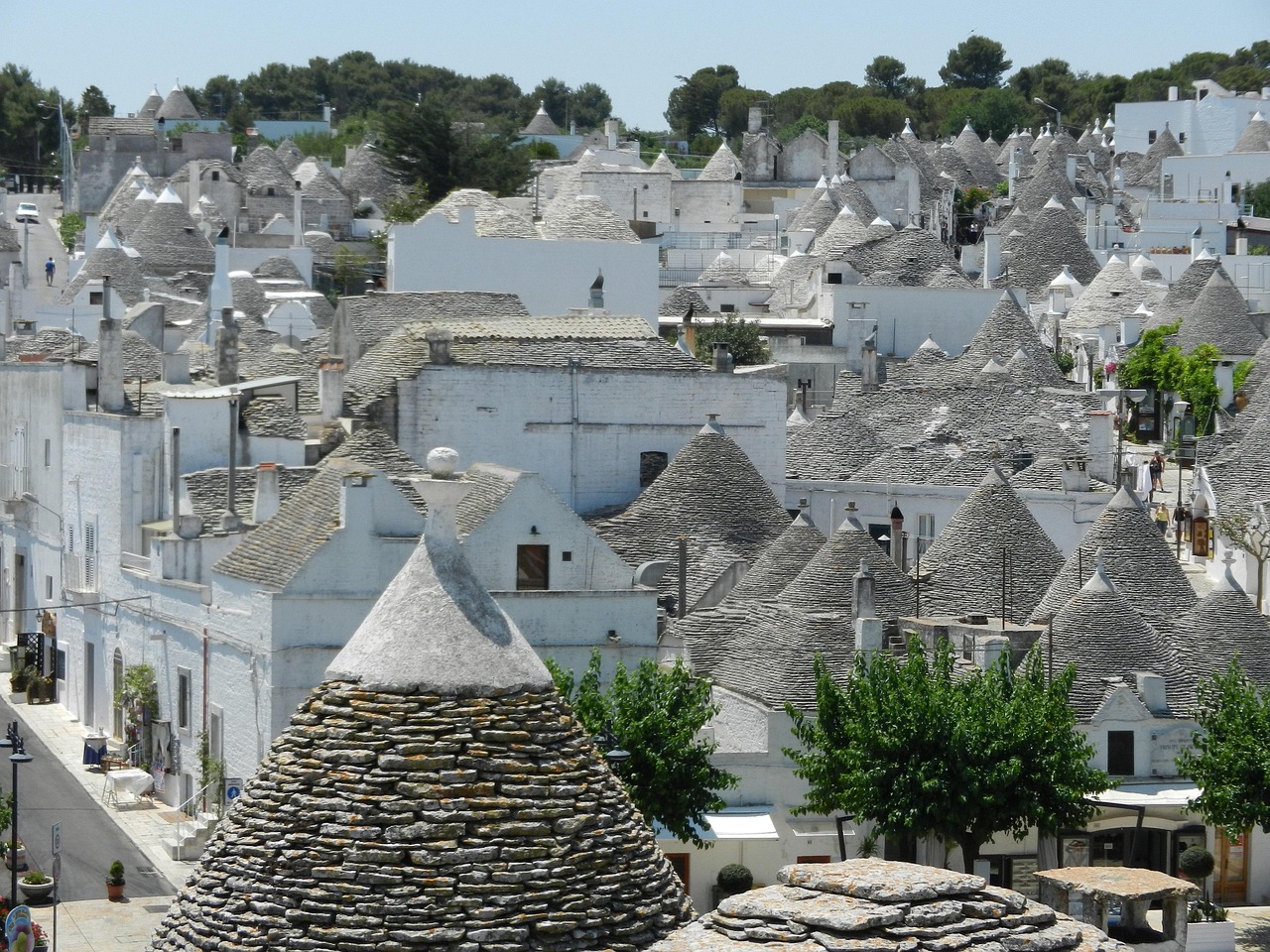 Trulli tipici della Valle d'Itria, paesaggio rurale con ulivi e colline verdi.